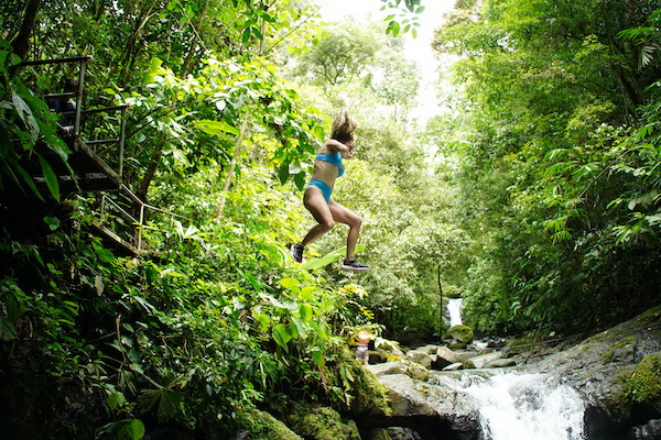 Woman jumping into a waterfall in Costa Rica