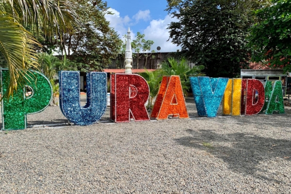 Large colorful 'PURA VIDA' letters display with textured design against tropical foliage background in Costa Rica