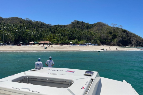 View from boat of pristine beach with palm trees and mountains in Costa Rica