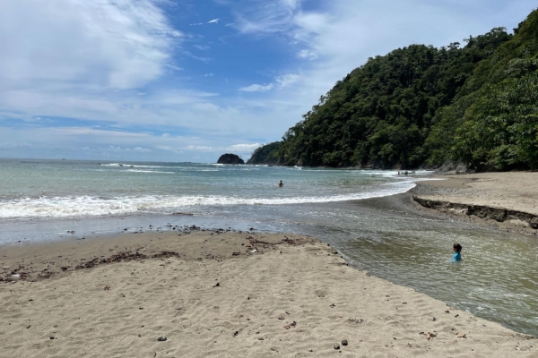 Scenic beach cove in Costa Rica with rocky cliffs, green mountains, and crystal clear waters