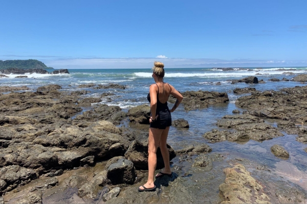 Person exploring volcanic rock formations and tide pools on Costa Rican beach