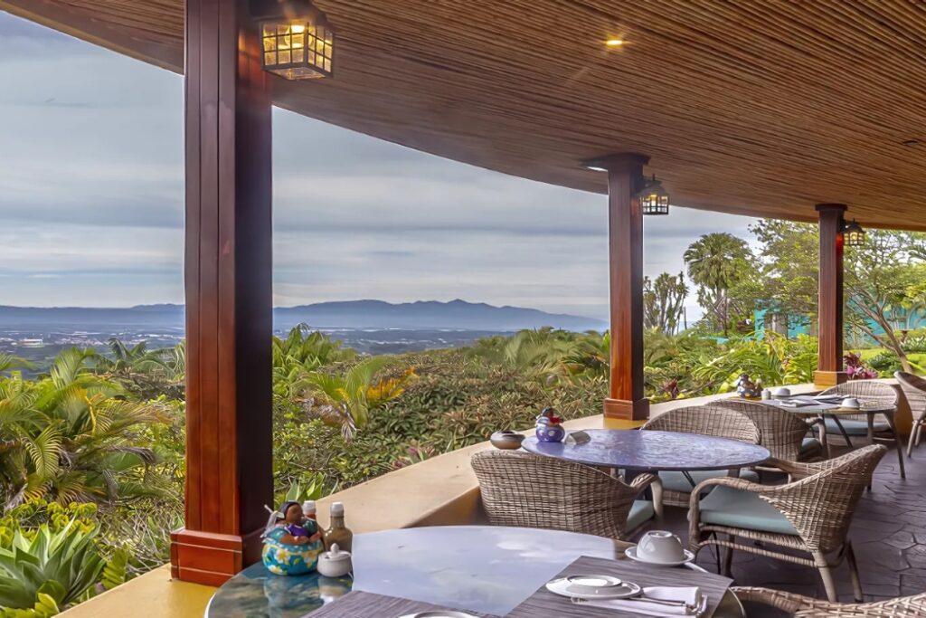 Scenic outdoor dining terrace with wooden beams, lanterns, and panoramic mountain views in Costa Rica