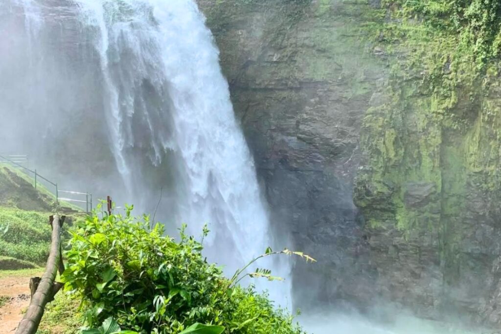 Powerful tropical waterfall cascading down green cliff face with viewing platform in Costa Rica