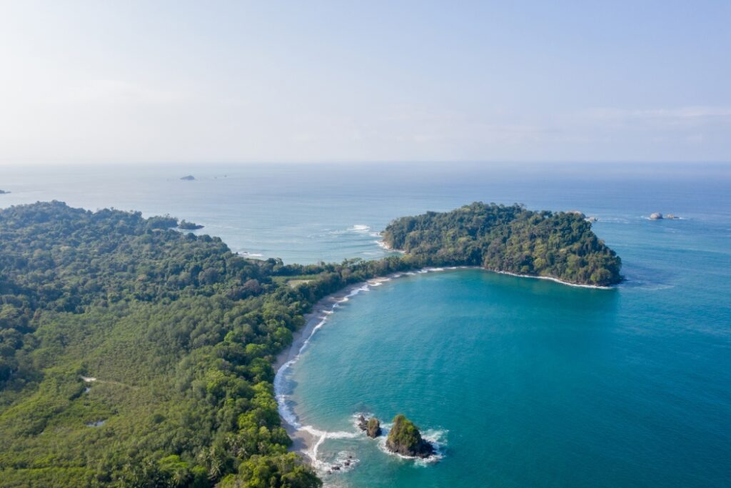 Aerial view of tropical coastline with turquoise water, beach, and forested peninsula in Costa Rica