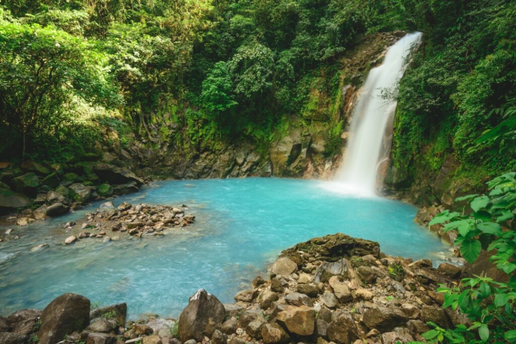 Vibrant blue waterfall and pool surrounded by tropical rainforest in Costa Rica