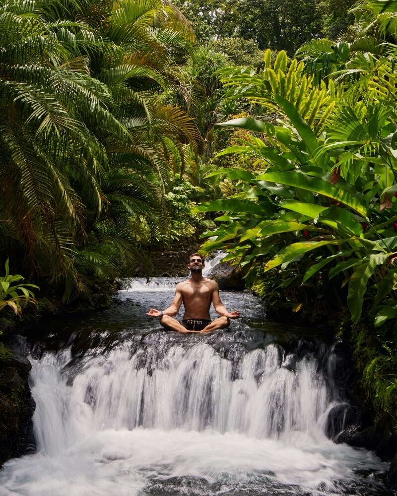 Man meditating on waterfall in Costa Rican rainforest